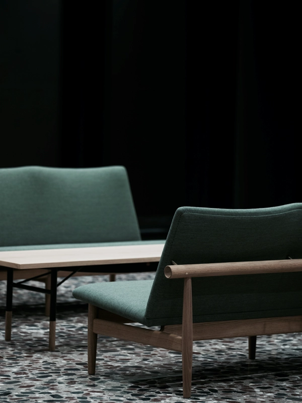 Japan Sofa by Finn Juhl featuring minimalist wooden frame with horizontal backrest and clean upholstered seating in contemporary setting.