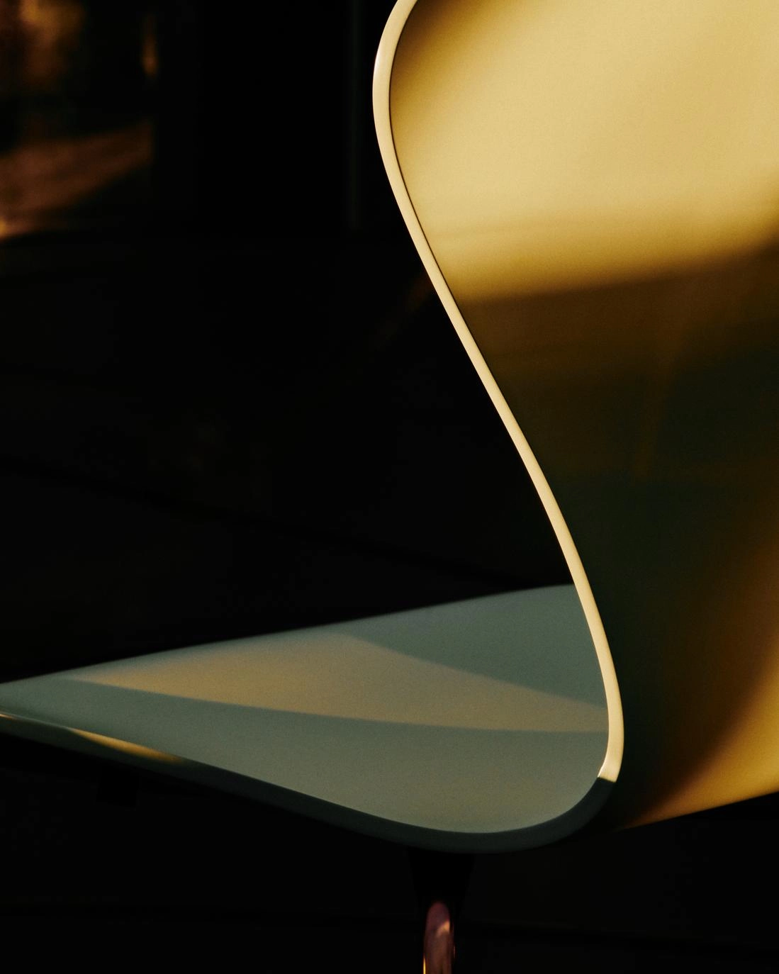 Close-up of the iridescent gold-toned rainbow base on Fritz Hansen's limited edition Series 7 chair designed by Arne Jacobsen