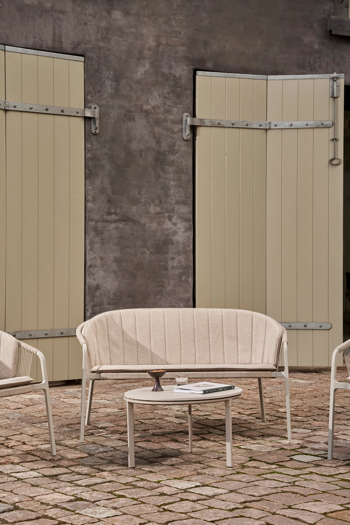 Vipp Lagrasse two-seater outdoor sofa in garden setting, featuring powder-coated aluminum frame and cord-woven design