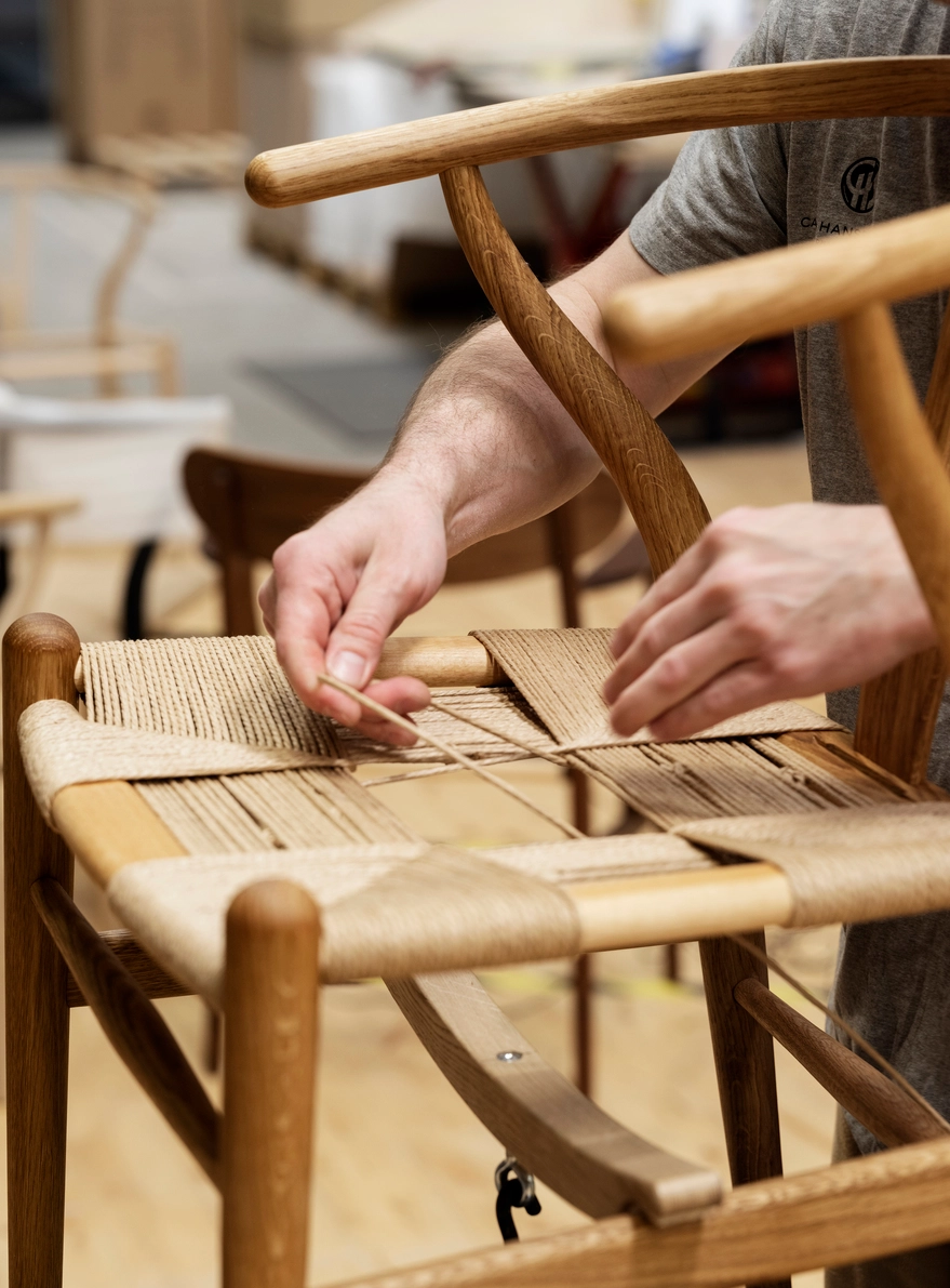 Carl Hansen & Søn craftsman hand-finishing an authentic Wishbone Chair in the company's Danish workshop
