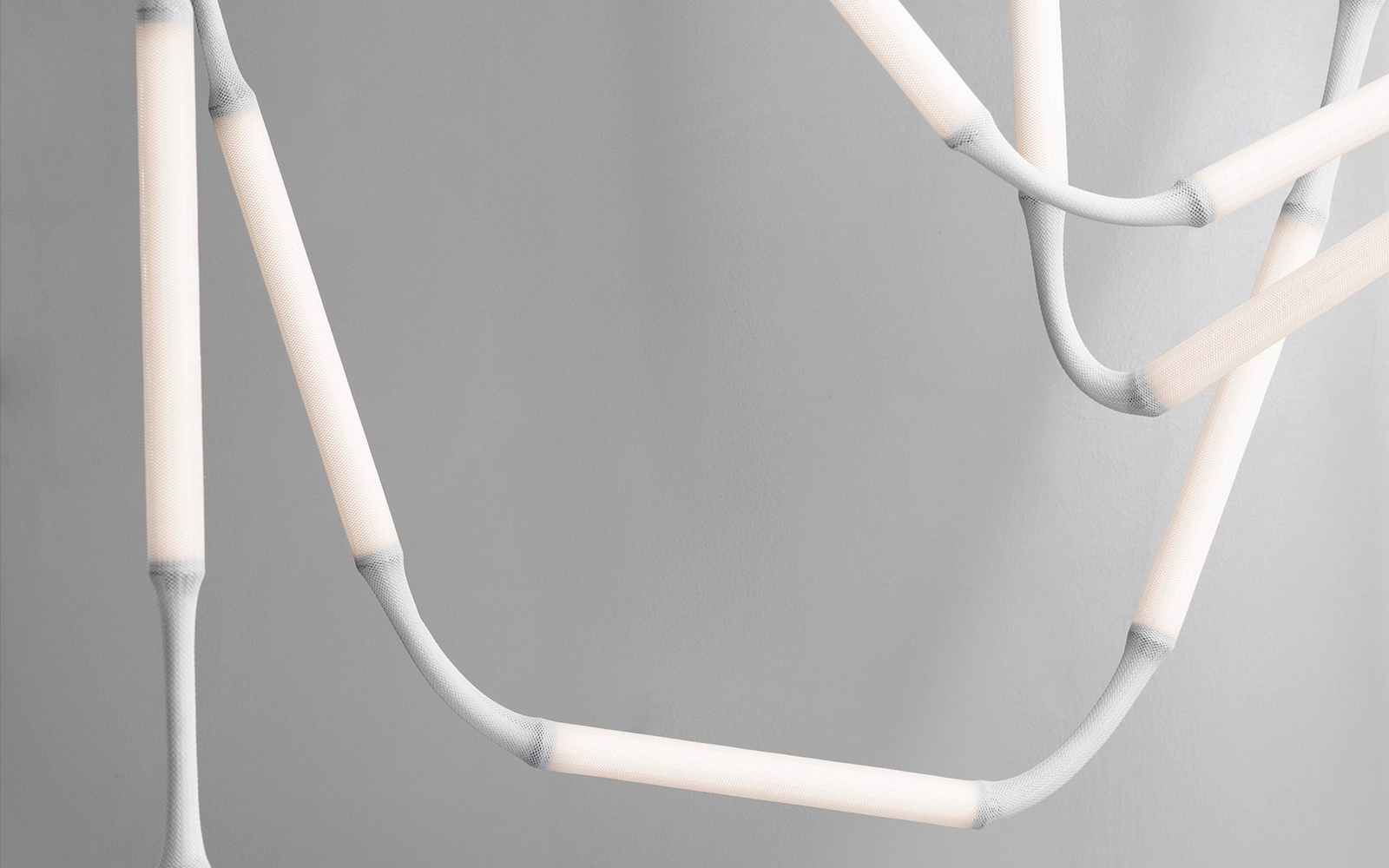 Close-up of Normann Copenhagen's Reb Lamp showing mesh fabric modules and metal tube base with integrated dimming function.