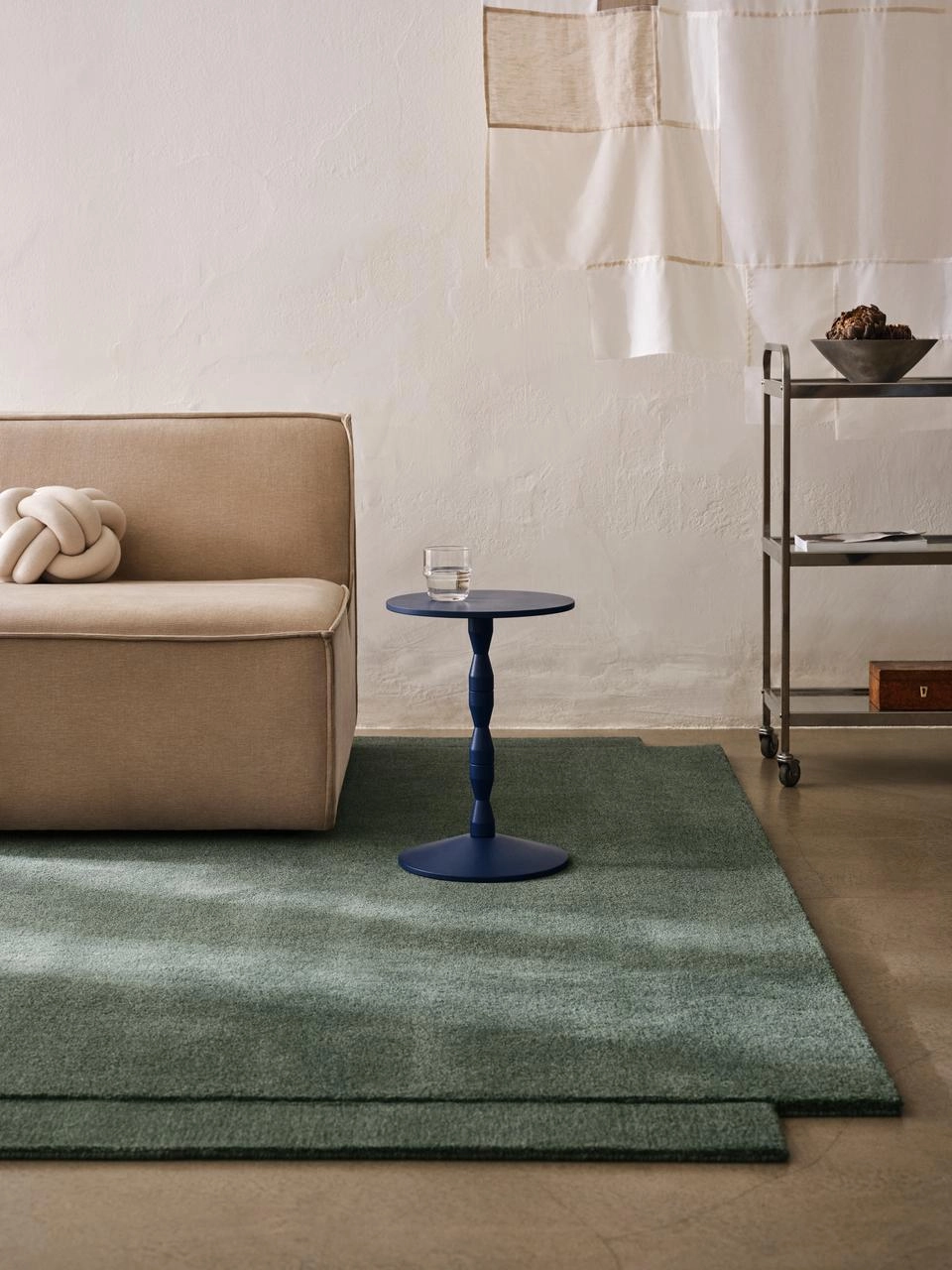 Matti Klenell's red Pedestal Table by Design House Stockholm in a living room setting displaying decorative objects